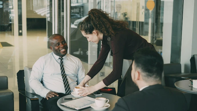 Woman serves coffee to men in office lobby.